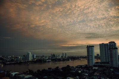 Sea by buildings against sky during sunset