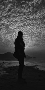 Silhouette woman standing on beach against sky during sunset