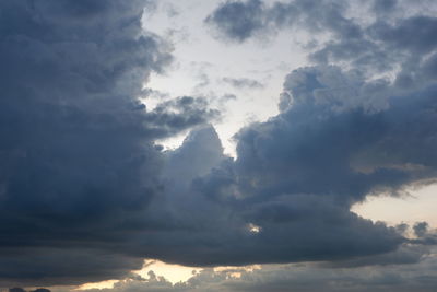 Low angle view of sunlight streaming through clouds