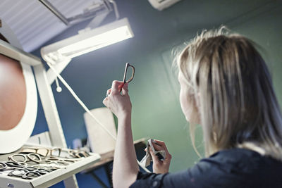 Female owner examining eyeglasses frame in workshop