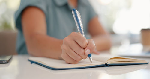 Midsection of woman writing in book