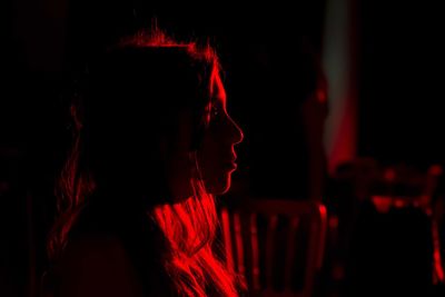 Side view of young woman looking away in darkroom