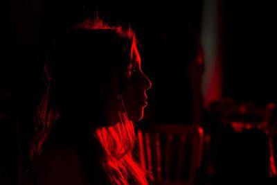 Side view of young woman looking away in darkroom