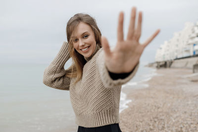 Portrait of young woman gesturing while standing at beach