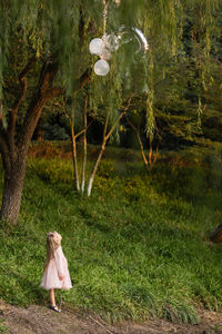 Girl standing by tree in forest