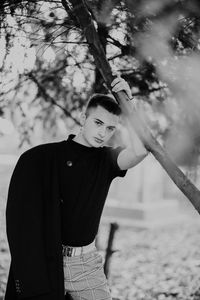 Portrait of young man standing against tree