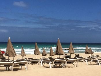 Chairs and tables on beach against sky