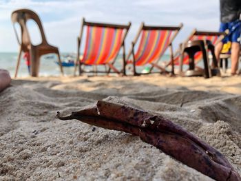 Close-up of chairs on beach against sky