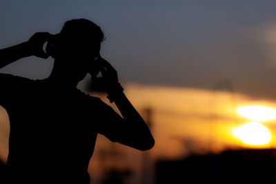 Silhouette man standing by sea against sky during sunset