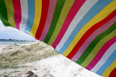 Multi colored towel on beach against sky