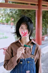 Portrait of woman smelling flower while standing on land