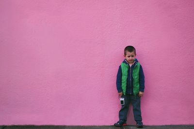 Portrait of boy standing against pink wall