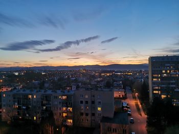 Illuminated cityscape against sky at sunset