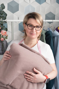 A real middle-aged woman blonde hair and overweight holds footer fabric from which she sews clothes