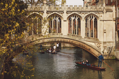 Boats rowing below bridge at canal