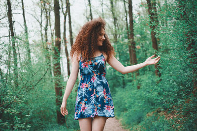 Low section of woman standing by tree in forest