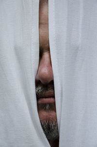 Close-up of bearded man behind curtain