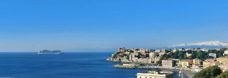 Panoramic view of sea and buildings against blue sky