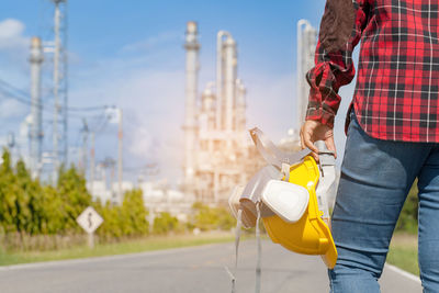 Midsection of man holding hardhat on road