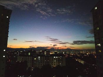 Illuminated buildings against sky at sunset