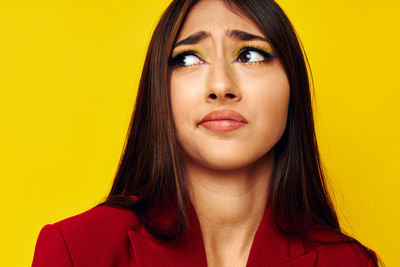 Young woman looking away against yellow background