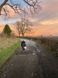 Rear view of person riding bicycle on road against sky