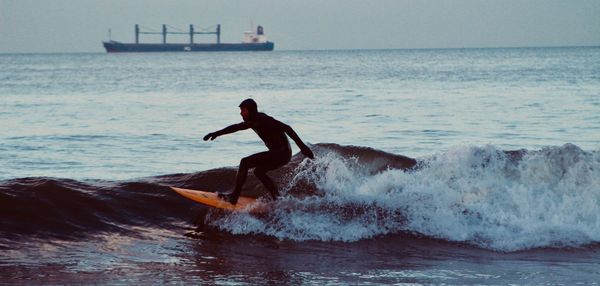 Man surfing in sea against sky