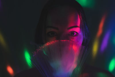 Close-up portrait of young woman holding multi colored fiber optic