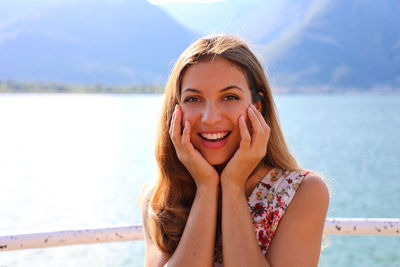 Portrait of a smiling young woman against water