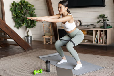 Full length of young woman exercising in gym