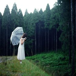 Woman with white umbrella standing on field