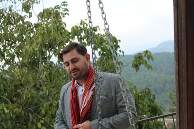 Smiling man standing against tree