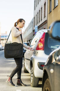 Side view of businesswoman entering car on street