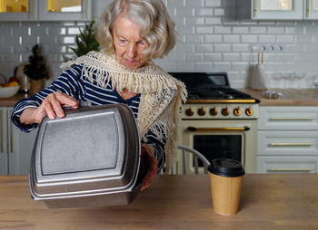 Lonely elderly woman opens food delivery from an online store