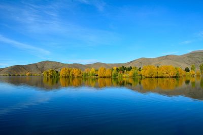 Scenic view of lake and mountains against blue sky