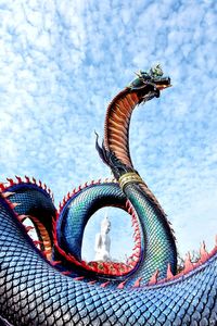 Low angle view of animal sculpture against blue sky