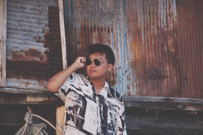 Portrait of young man standing against wall