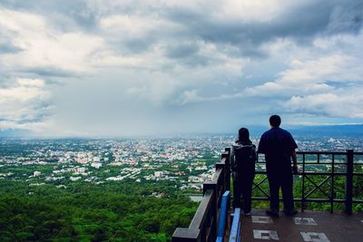 Rear view of man looking at cityscape against sky