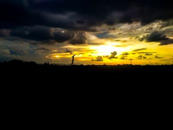 Silhouette landscape against dramatic sky during sunset