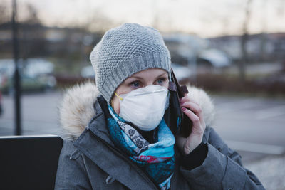 Woman wearing protective mask talking via cell phone