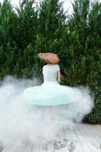 Woman dancing amidst smoke against trees