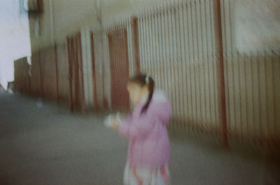 Blurred image of woman walking by wall