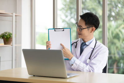 Rear view of man using laptop on table
