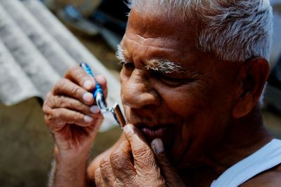 Close-up of man shaving outdoors