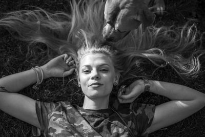 High angle portrait of young woman with dog lying on grassy field