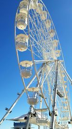 Low angle view of ferris wheel against clear blue sky