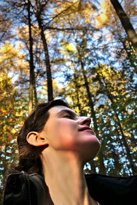 Low angle portrait of young woman against plants