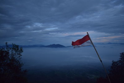 Low angle view of red flag on mountain against sky