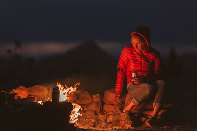 Female camper stares into fire while drinking beer on blm land of utah