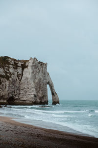 Rock formation on beach against sky